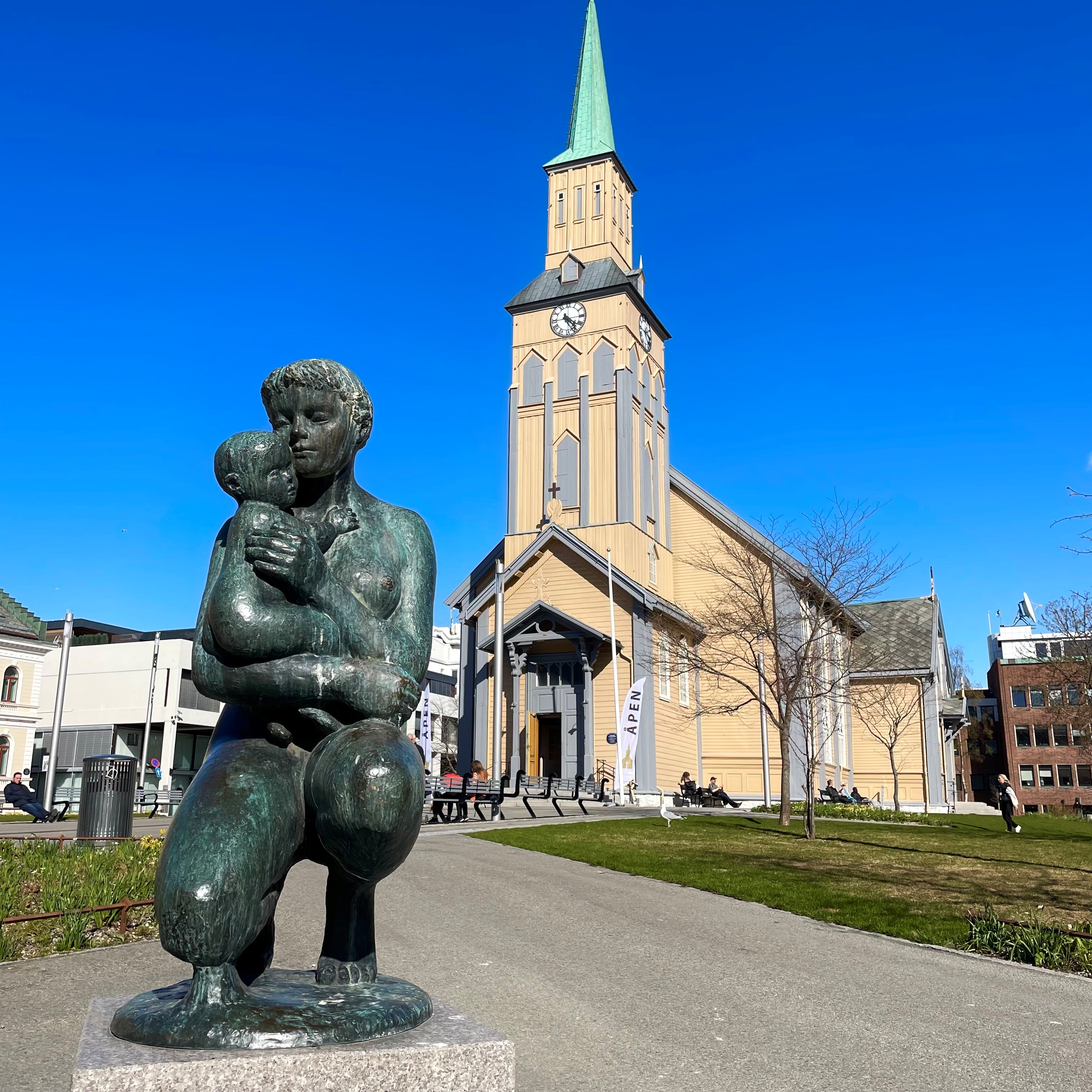 Kirka sett fra veien, med mor og barm-statue i forkant